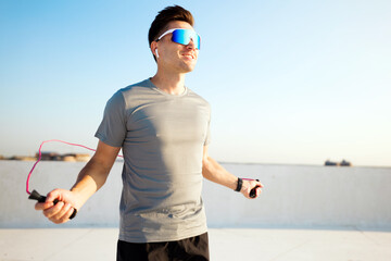Man skips rope on rooftop in bright sunlight