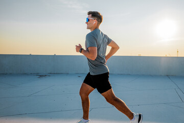 Man running on rooftop during sunset
