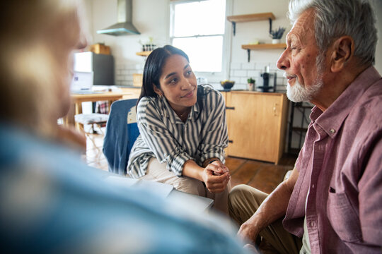 Adult woman listening to senior man at home, thoughtful
