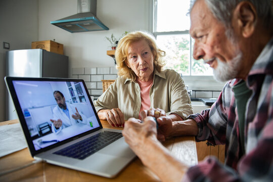 Senior couple concerned in telehealth consultation at home kitchen