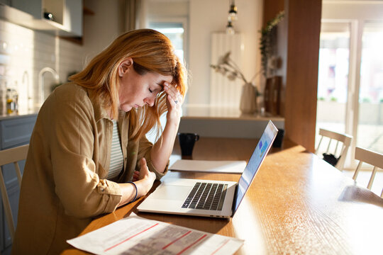 Adult woman worried about bills on laptop at home