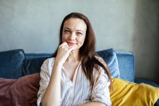 Young adult woman smiling on sofa at home