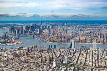 An expansive aerial view of New York City showing the East River with the Brooklyn, Manhattan, and Williamsburg bridges.