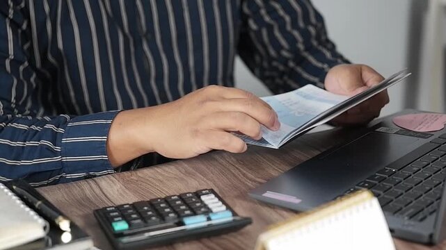Men's hands holding savings books and preparing budgets. Looking at savings books in front of computers.calculating household budgets and expenses.Insurance or mortgages.Household financial management