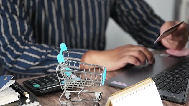 A happy man, a laptop, and online banking with a credit card for virtual payments or remote shopping at home. A smiling young man or shopper, a debit card, or a computer for online purchases or financ