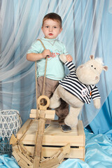 Adorable toddler in striped shirt standing on a wooden crate with a plush hippo toy