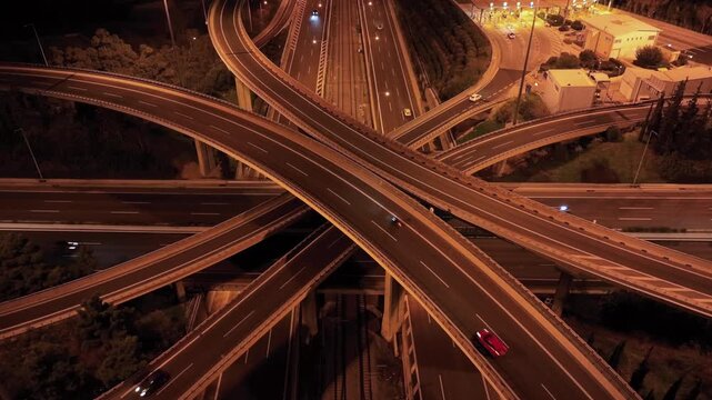 Aerial drone top down hyper lapse loop night video of illuminated urban elevated road junction and interchange overpass in city with light traffic