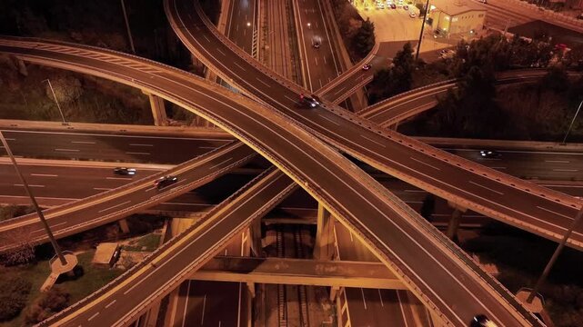 Aerial drone top down hyper lapse loop night video of illuminated urban elevated road junction and interchange overpass in city with light traffic