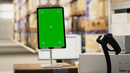 Fulfillment center with chroma key on tablet handling delivery service, order processing with a scanner and computer at the desk. Large business activity with reliable logistics and packaging.