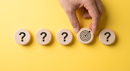 hand placing target goal on question marks wooden blocks