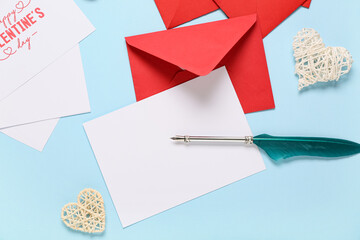 Composition with red envelopes, blank card and feather on blue background. Valentine's Day...