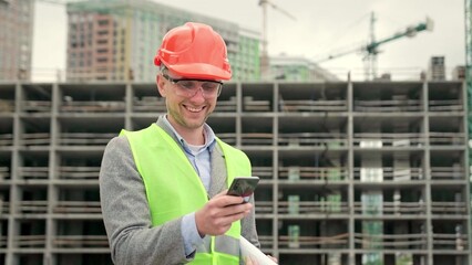 Builder inspects territory of construction site outside, use gadget