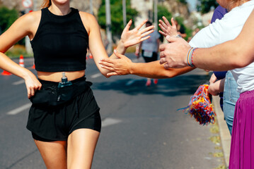 Hands of people cheering up running woman