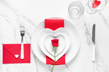 Table setting for Valentine's Day with envelope and rose flower on marble background