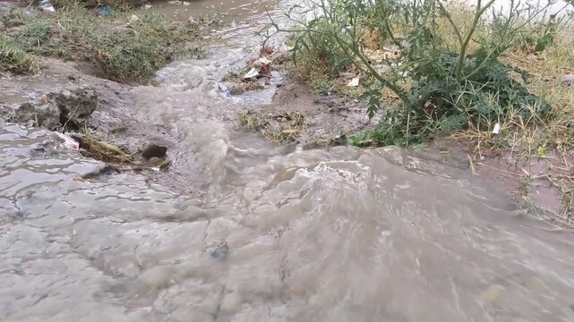 Fast flowing muddy rainwater through rural drainage channel causing erosion after heavy rainfall