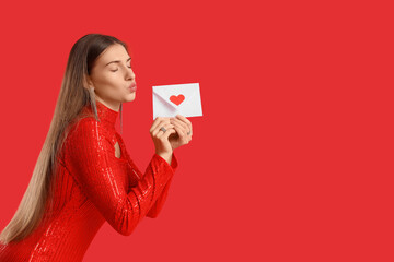 Beautiful woman with love letter blowing kiss on red background. Valentine's Day celebration
