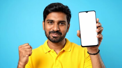 A smiling man in a yellow shirt holds a phone with a blank screen, set against a vibrant blue backdrop, showcasing a modern technology and positive emotion.