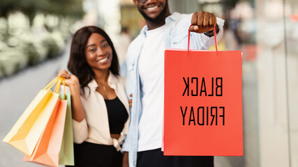 Black Friday Sales Concept. Closeup Of African American Man Hugging Woman, Holding And Showing Red...