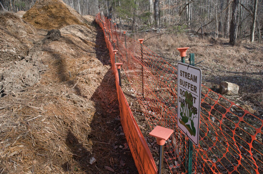 Sign and geofencing mark a stream buffer area for erosion control in a wooded region - copy space