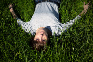 Frau liegt im gr&uuml;nen Gras und blickt nach oben