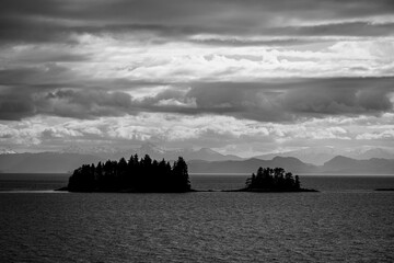 Dramatic cloudscape and distant snow clad mountains frame islands of the inside passage in the Pacific Northwest