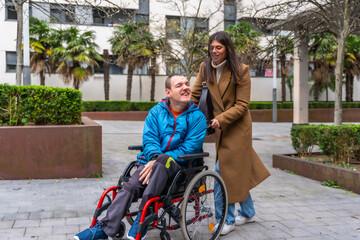 Caregiver pushing man in wheelchair outdoors, inclusion and support