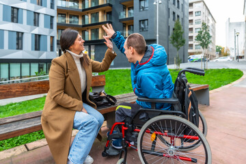 Caregiver high fiving boy with disability outdoors