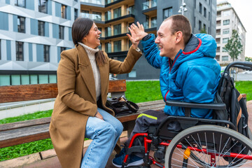 Woman and man with disability high fiving outdoors