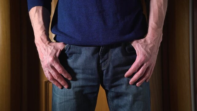 Annoyed adult man is nervously gesturing with his fingers. A close-up of a palms of an impatient man standing in a room with his hands in his jeans pockets. 4K
