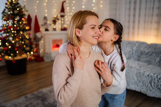 Daughter kissing mother on cheek during Christmas holiday at home