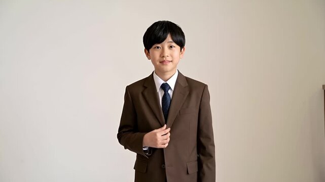 日本の中学校入学式を想定した、12〜13歳の少年を描いたフォトリアルなポートレートです。
茶色のブレザーとダークスラックスを着用し、清潔感のある正装スタイルになっています。
白背景と柔らかなスタジオ照明により、落ち着いた雰囲気と余白を活かした構図です。