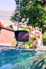 Beautiful antique turquoise car with red lights. Well-maintained and well-painted vehicle, refurbished. Seen from the side. Parked in an outdoor park at sunset, with natural light.