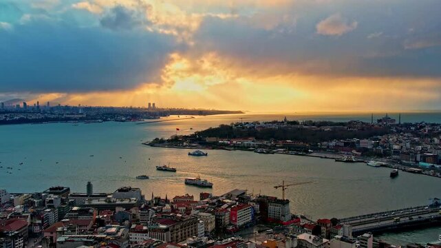 Drone footage showing the Galata Bridge, Sarayburnu, Topkapi Palace, Hagia Sophia, the Blue Mosque and the Golden Horn illuminated by dramatic sunset colors over Istanbul.
