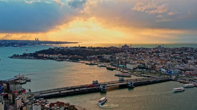 Drone footage showing the Galata Bridge, Sarayburnu, Topkapi Palace, Hagia Sophia, the Blue Mosque and the Golden Horn illuminated by dramatic sunset colors over Istanbul.
