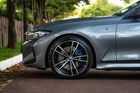 Grey BMW 320i front wheel and blue caliper, Sports sedan detail shot