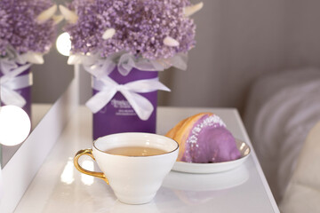 Cup of tea and berry croissant, bouquet of violet flowers