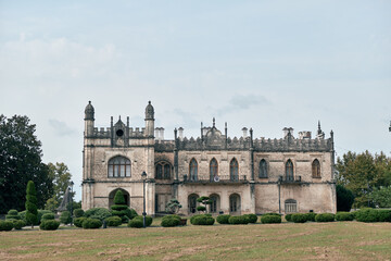 Fototapeta premium mansion historic estate architecture castle manor house with lawn and trees in overcast sky detailed facade and stone exterior
