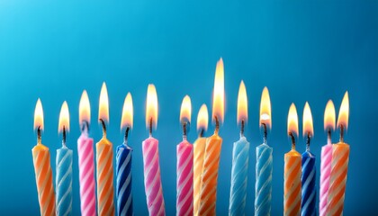 Lit Multicolored Birthday Candles Over Blue Background Creating Warm Festive Glow With Copy Space For Message Or Design Perfect For Birthday Party Invitations Or Greetings