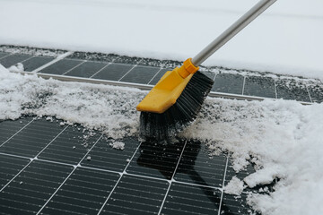 solar panel being cleaned from snow using a brush during winter. Renewable energy maintenance concept, cold weather conditions, sustainable and eco-friendly power generation.
