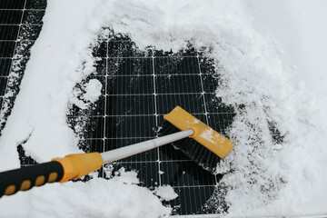  sustainable and eco-friendly power generation. Cleaning snow from solar panel in winter with brush.Close-up view of a solar panel being cleaned from snow using a brush during winter. 