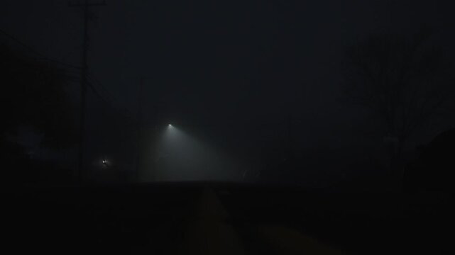 Dark foggy street with single streetlight beam