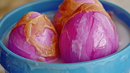 Garlic cloves in a blue bucket, unpeeled and whole.