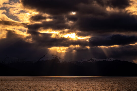 Dramatic sunbeams striking snow-capped mountains on the Alaskan Coast. - Powered by Adobe