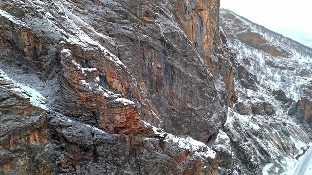 A dramatic aerial view of snowy rocky cliffs and rugged winter mountain terrain in Munzur Valley. Ideal for nature, geography, winter landscapes and cinematic drone footage.