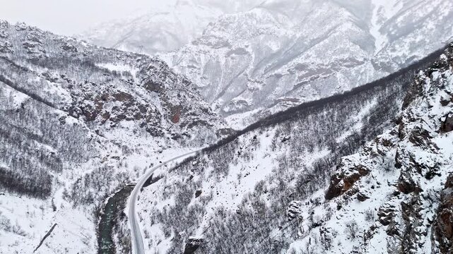 A stunning aerial view of snowy cliffs, a winding river and a mountain road in Munzur Valley. Ideal for nature, winter landscapes, geography visuals and cinematic drone footage.