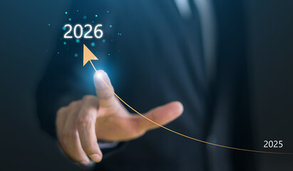 Businessman pointing at rising arrow graph from 2025 to 2026, Concept of financial growth, corporate profit increase, business success, economic improvement, future investment and market forecast