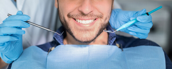 Unrecognizable male patient having teeth whitening procedure at modern dental clinic, smiling at...