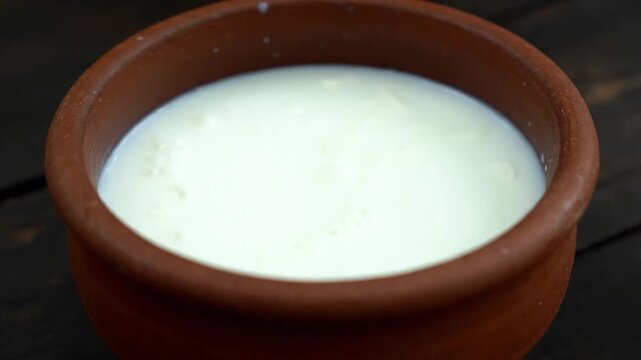 Fresh Yogurt in Clay Pot Close-Up, Plain White Yogurt with Brown Clay Pot on Dark Brown Wooden Surface