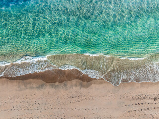 drone view of waves crashing on sandy beach