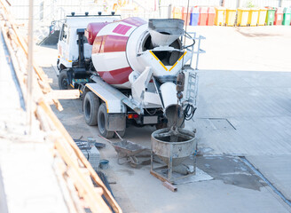 A construction series showing a cement mixer truck loading wet concrete into a crane bucket